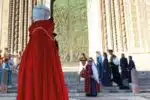 corteo-delle-dame-orvieto – Orvieto | Orvietoviva a Group of People in Medieval Robes Outside an Ornate Building Doorway; a Person in a Bright Red Cloak Dominates the Foreground.